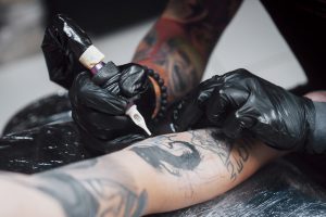 Tätowierer arbeitet an einem Unterarm-Tattoo.