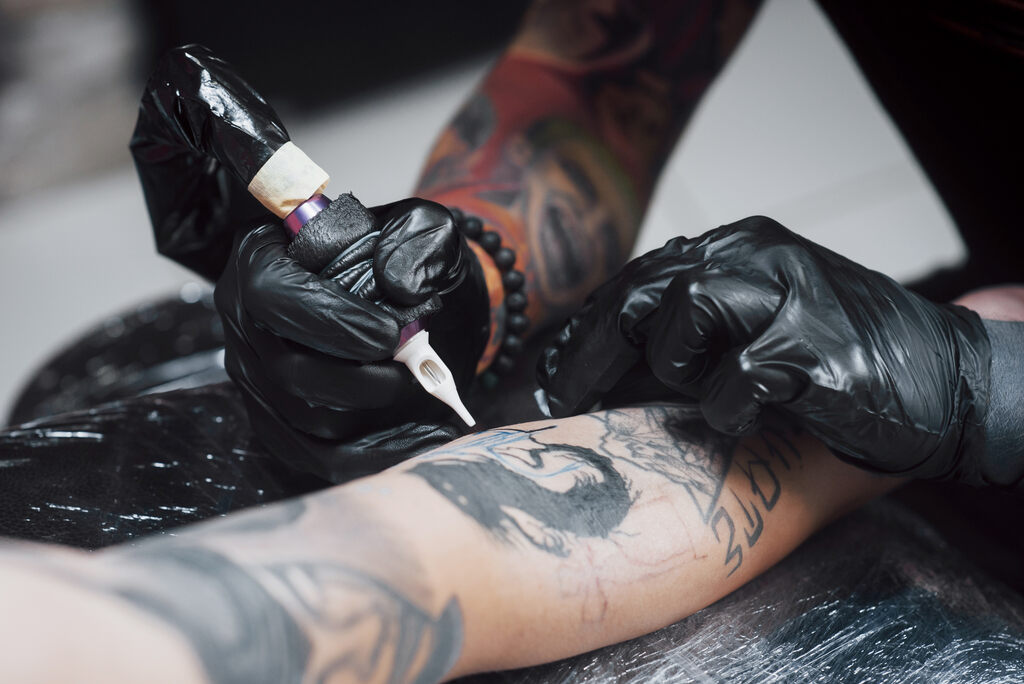 Tätowierer arbeitet an einem Unterarm-Tattoo.